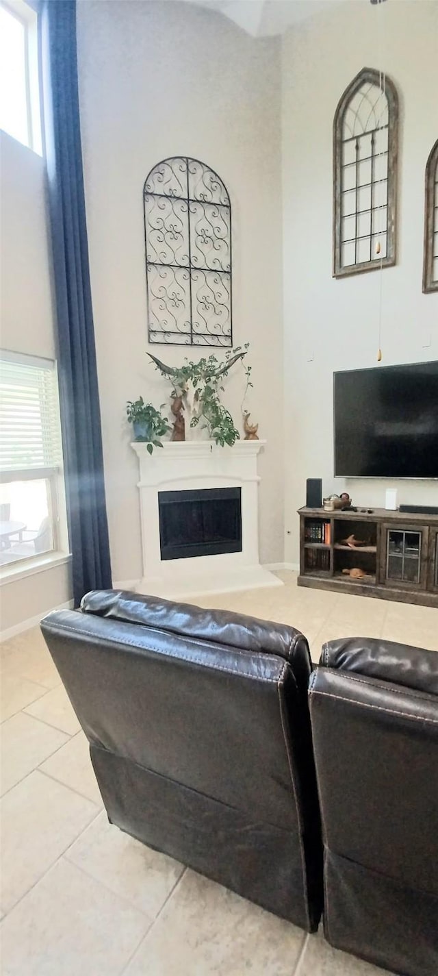living room featuring a fireplace with raised hearth, tile patterned flooring, and healthy amount of natural light