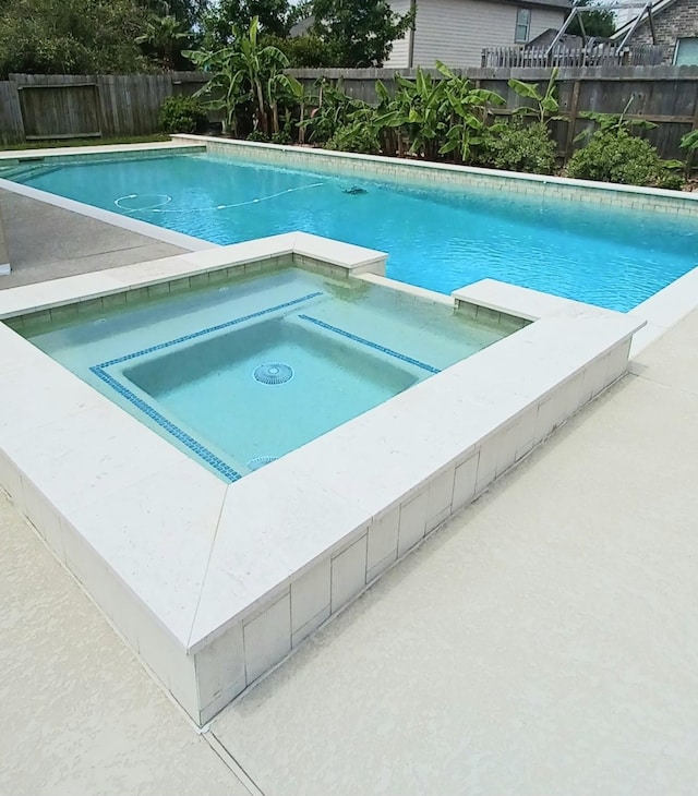 view of swimming pool with a fenced backyard and an in-ground hot tub