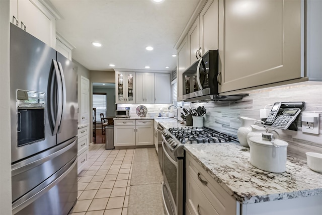 15223 Hillside Park Way, Cypress, TX 77433 - kitchen featuring appliances with stainless steel finishes, decorative backsplash, light tile patterned floors, recessed lighting, and glass insert cabinets