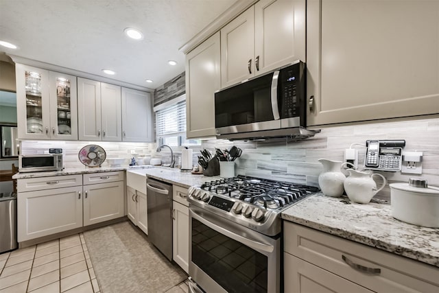 15223 Hillside Park Way, Cypress, TX 77433 - kitchen with stainless steel appliances, a sink, backsplash, glass insert cabinets, and recessed lighting