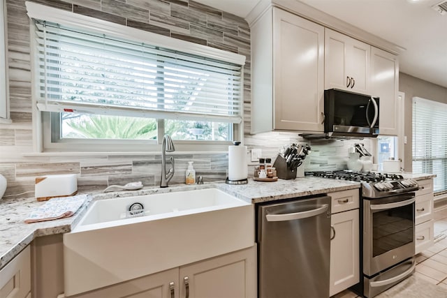 15223 Hillside Park Way, Cypress, TX 77433 - kitchen featuring stainless steel appliances, decorative backsplash, a sink, light stone counters, and light tile patterned floors