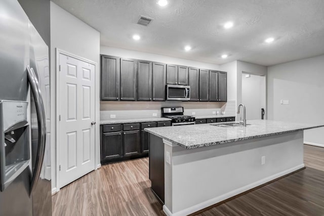 15335 Oakheath Colony Ln, Houston, TX 77044 - kitchen with stainless steel appliances, a sink, light wood-style floors, recessed lighting, and a textured ceiling