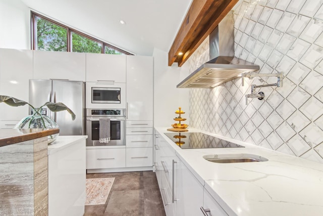 kitchen featuring appliances with stainless steel finishes, wall chimney range hood, modern cabinets, decorative backsplash, and white cabinetry