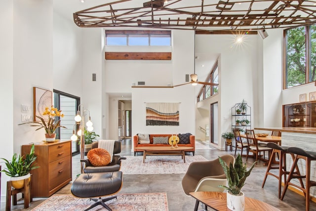 living room featuring a high ceiling, healthy amount of natural light, and finished concrete flooring