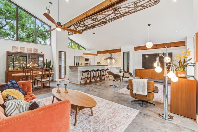 living area featuring high vaulted ceiling, finished concrete flooring, ceiling fan, and beam ceiling