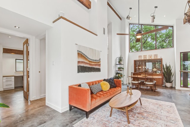 living area with a towering ceiling, baseboards, and ceiling fan