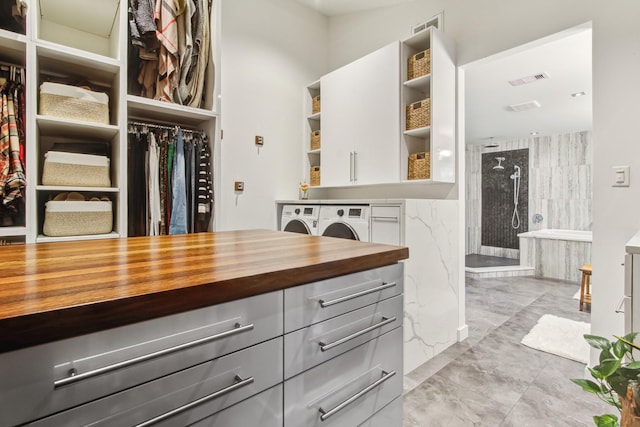 walk in closet with light marble finish flooring and independent washer and dryer