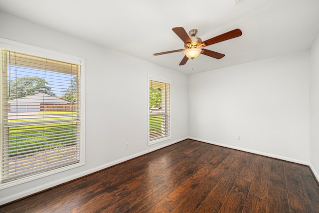 empty room with dark wood-style floors, a ceiling fan, and baseboards