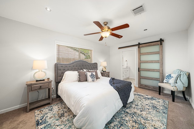 bedroom with a barn door, light colored carpet, baseboards, ceiling fan, and connected bathroom