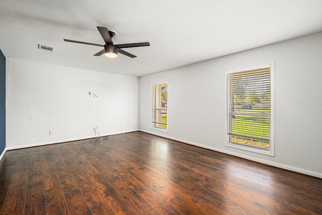 spare room with a ceiling fan, dark wood-type flooring, and baseboards