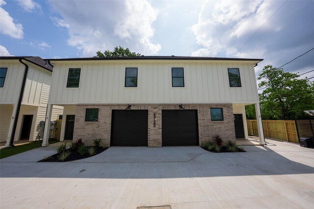 modern farmhouse style home featuring brick siding, concrete driveway, a garage, and fence