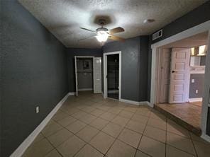 tiled empty room featuring a ceiling fan and baseboards