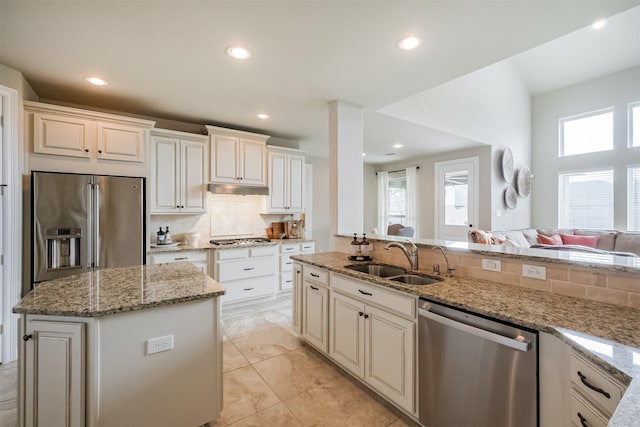 kitchen featuring appliances with stainless steel finishes, a sink, decorative backsplash, recessed lighting, and light stone countertops