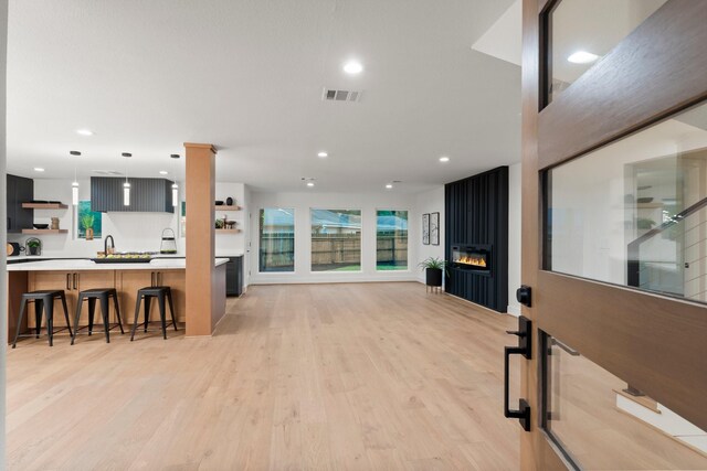 living room with a large fireplace, recessed lighting, light wood-style floors, and plenty of natural light
