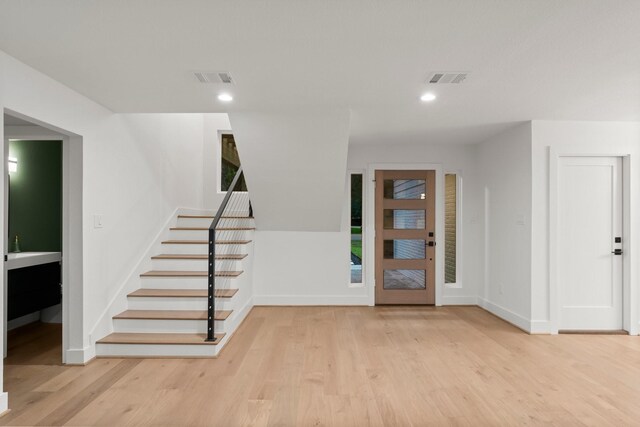 foyer entrance with stairway, baseboards, wood finished floors, and recessed lighting
