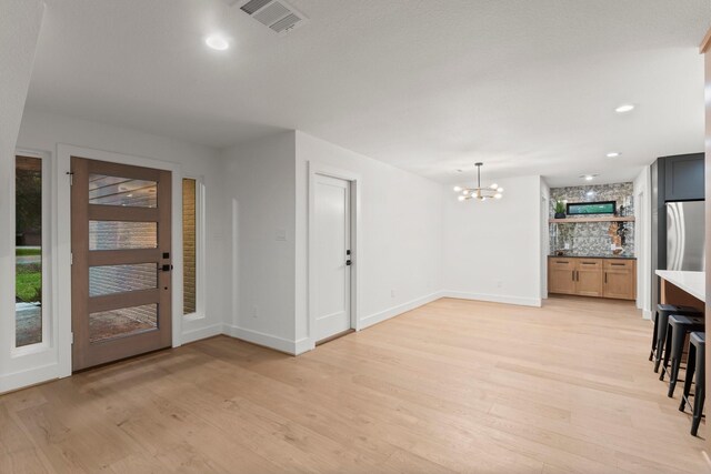entrance foyer with a chandelier, light wood finished floors, baseboards, and recessed lighting