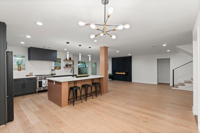kitchen featuring high end stainless steel range, a breakfast bar, light countertops, light wood finished floors, and recessed lighting