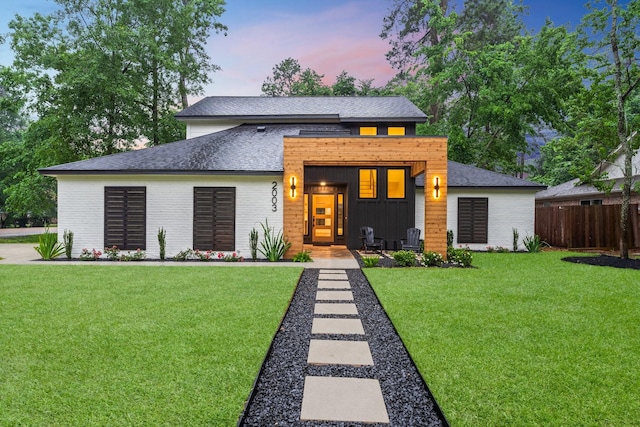 contemporary home with brick siding, board and batten siding, and a shingled roof