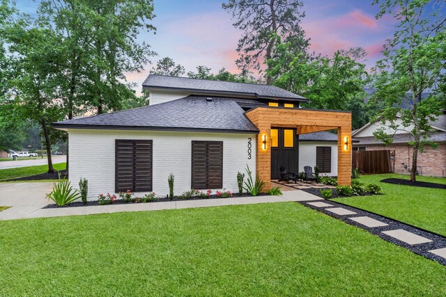 view of front of home featuring roof with shingles and brick siding