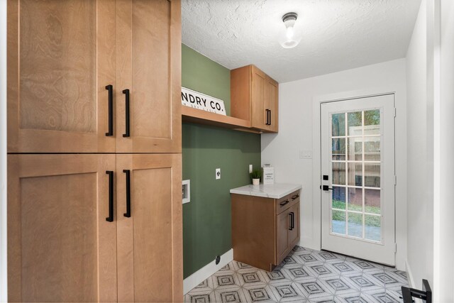 laundry room featuring cabinet space, hookup for a washing machine, hookup for an electric dryer, light flooring, and a textured ceiling