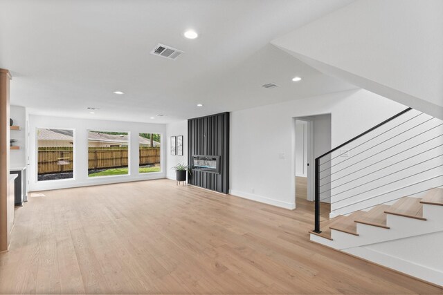 unfurnished living room with light wood finished floors, stairs, recessed lighting, and baseboards