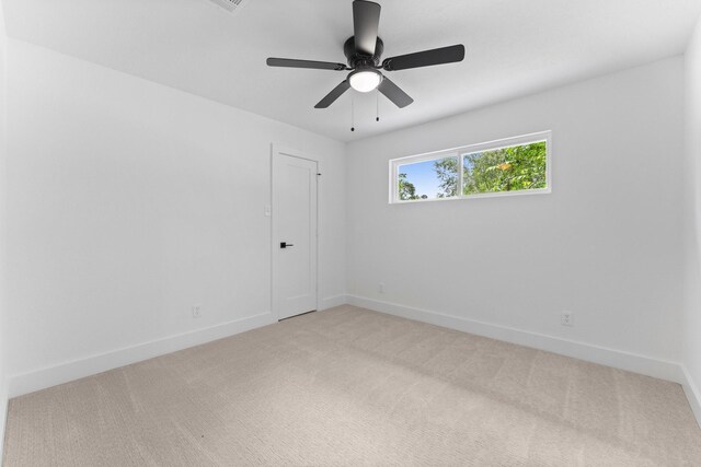 unfurnished room with light colored carpet, a ceiling fan, and baseboards