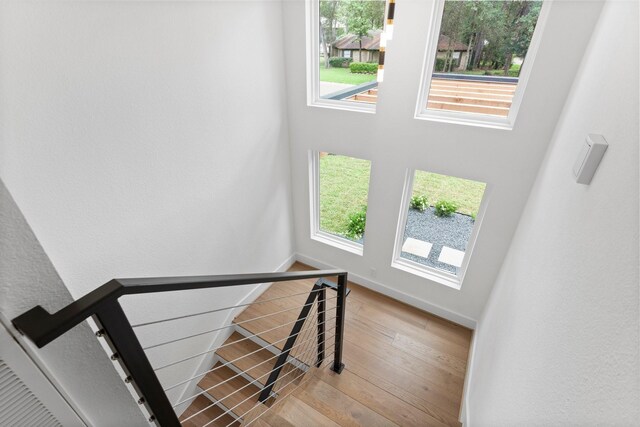 stairs featuring wood finished floors, healthy amount of natural light, and baseboards