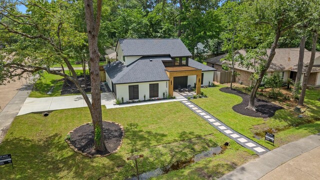 2003 Longstraw Pl, The Woodlands, TX 77380 - rear view of property featuring roof with shingles, a lawn, concrete driveway, and stairs