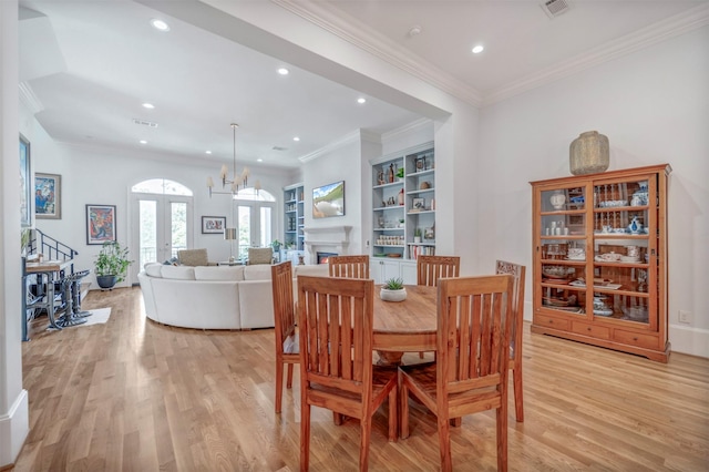 7119 Janet St, Houston, TX 77055 - dining area with light wood finished floors, recessed lighting, french doors, a warm lit fireplace, and ornamental molding
