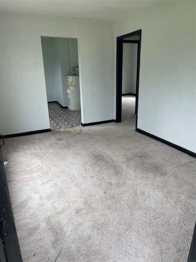 carpeted empty room featuring electric water heater and baseboards