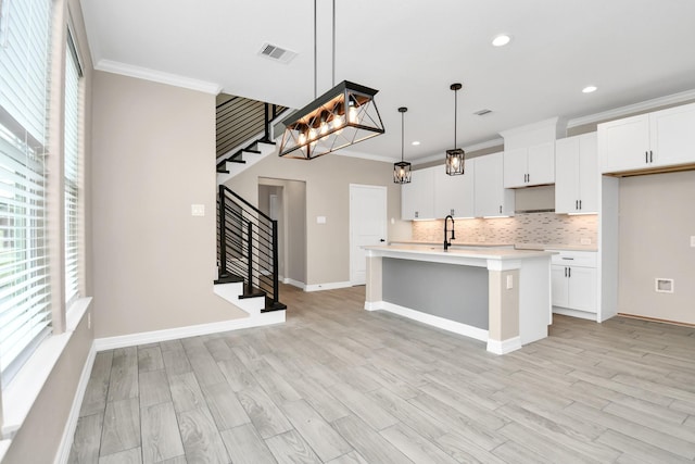 8103 Venus Dr, Houston, TX 77088 - kitchen featuring ornamental molding, light countertops, decorative backsplash, a kitchen island with sink, and white cabinetry