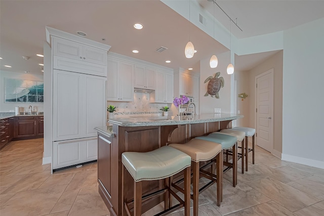 801 E Beach Dr Unit Tw2008, Galveston, TX 77550 - kitchen with a sink, a kitchen breakfast bar, white cabinets, decorative backsplash, and decorative light fixtures