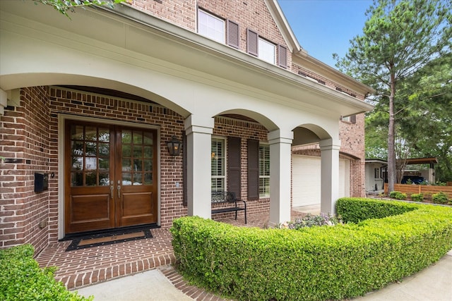 view of exterior entry featuring brick siding, french doors, and a porch