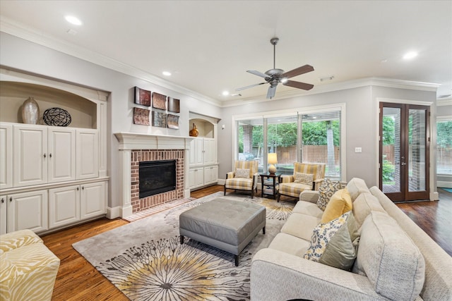 living area featuring wood finished floors, recessed lighting, ceiling fan, crown molding, and a fireplace