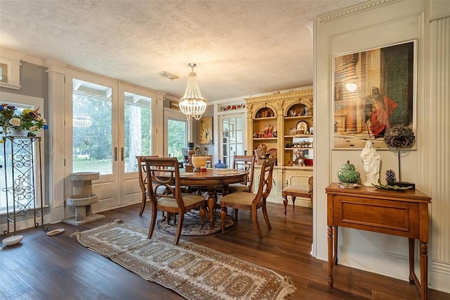 dining space with french doors, a chandelier, dark wood-style flooring, and a textured ceiling