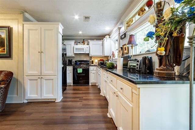 kitchen featuring gas stove, white microwave, dark countertops, dark wood-style floors, and ornamental molding