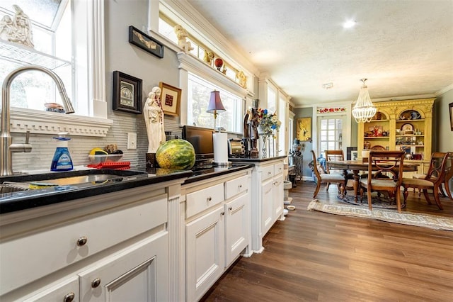 kitchen with a sink, dark countertops, decorative backsplash, a textured ceiling, and crown molding