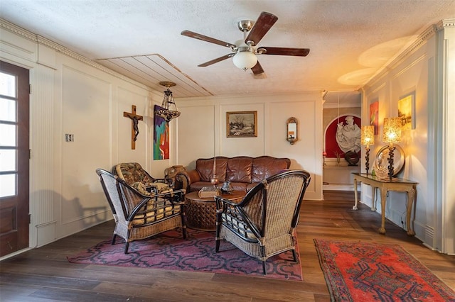 living room featuring a decorative wall, a ceiling fan, wood finished floors, and a textured ceiling