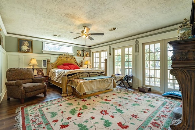 bedroom featuring access to exterior, ornamental molding, a textured ceiling, wood finished floors, and french doors