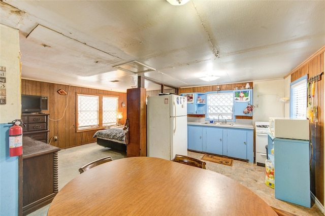 1577 Channel Dr, Brazoria, TX 77422 - kitchen with white appliances, wooden walls, a sink, and blue cabinetry