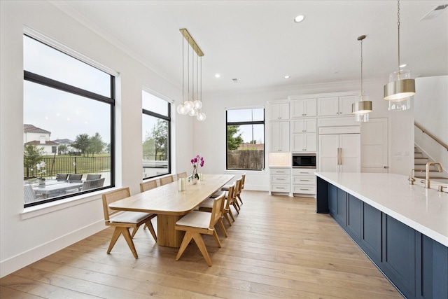 dining room with ornamental molding, light wood-style floors, recessed lighting, and baseboards