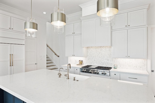 kitchen with stainless steel gas stovetop, paneled fridge, backsplash, white cabinetry, and light stone countertops