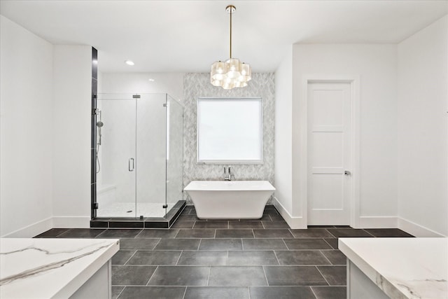 full bathroom featuring a chandelier, a shower stall, a freestanding bath, tile patterned floors, and baseboards