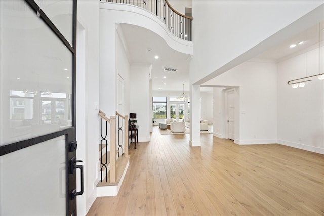 foyer entrance featuring light wood finished floors, a towering ceiling, recessed lighting, and baseboards