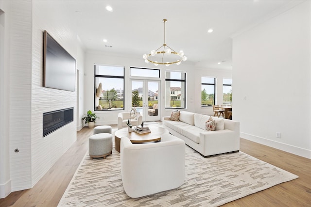 living room featuring a chandelier, baseboards, recessed lighting, light wood finished floors, and crown molding
