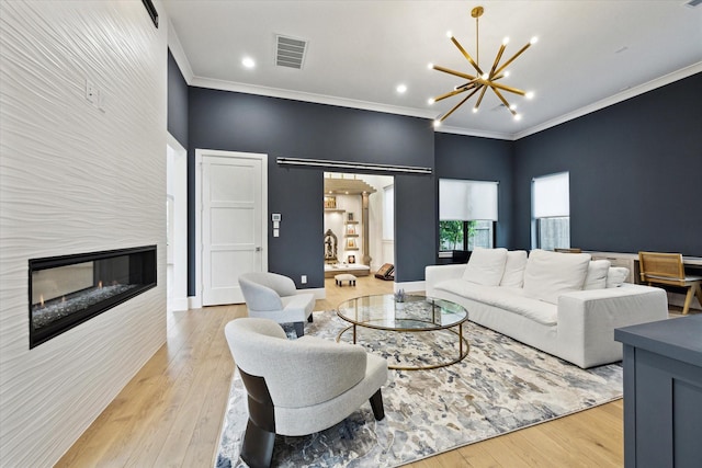 living room with a fireplace, a chandelier, crown molding, light wood finished floors, and a towering ceiling