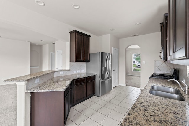 10015 Chase Ct, Baytown, TX 77521 - kitchen with a sink, range with gas cooktop, stainless steel fridge, light tile patterned floors, and arched walkways