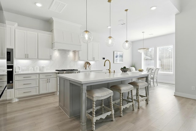 kitchen featuring a sink, decorative backsplash, light countertops, baseboards, and a breakfast bar area