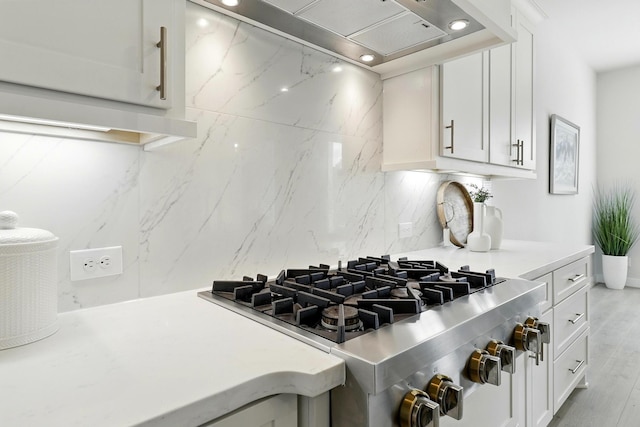 kitchen featuring wall chimney exhaust hood, light countertops, white cabinetry, and recessed lighting