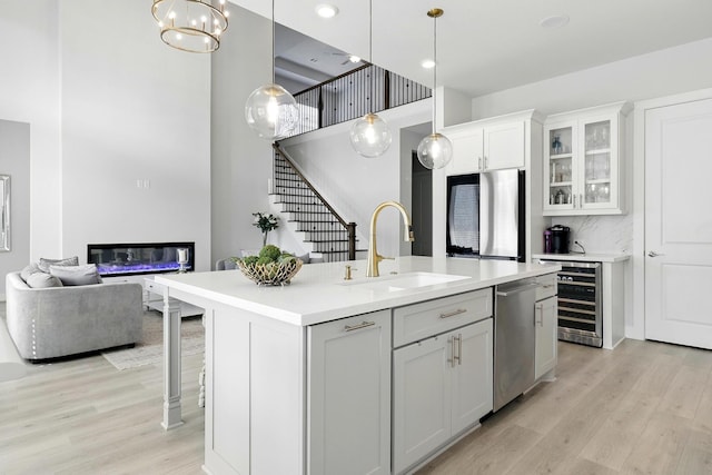 26923 Arethusa Ct, Spring, TX 77389 - kitchen with a sink, wine cooler, stainless steel dishwasher, a glass covered fireplace, and light wood finished floors